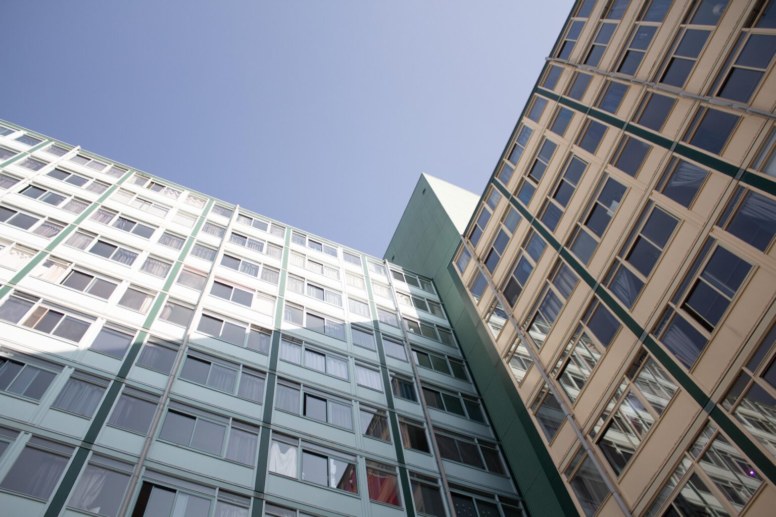 The Municipal Council wants Delft to demand more shared student houses Een hoog flatgebouw van onderaf gezien. Op de achtergrond een blauwe lucht