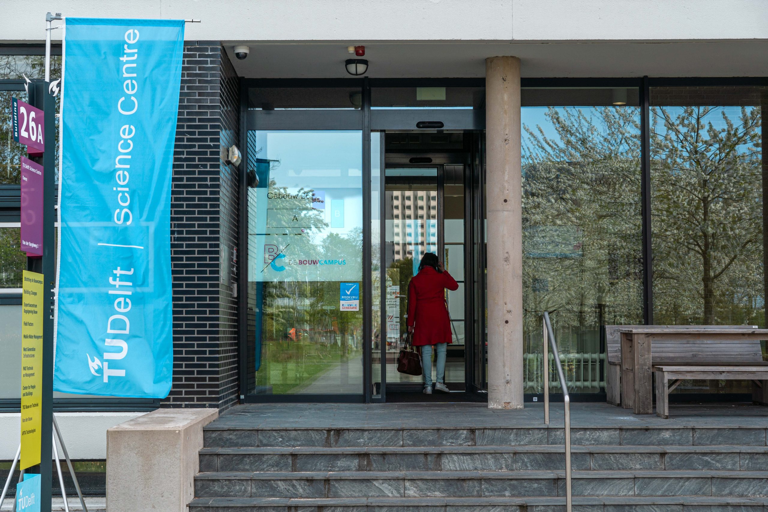 ScienceCentre_Bouwcampus_4_ThijsvanReeuwijk de ingang van een gebouw, waar iemand naar binnen loopt, van achteren en vanuit de verte gezien